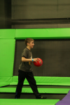 Boy Holding Dodgeball Standing on Trampoline at Indoor Fun Park
